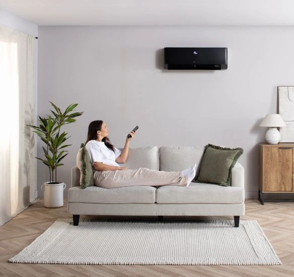 Woman sitting on sofa turning on air con